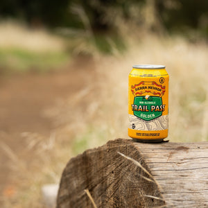 Thumbnail of Sierra Nevada Brewing Co. Trail Pass Golden Non-Alcoholic Brew - A refreshing can of Trail Pass Golden sits atop a fallen log near a hiking trail