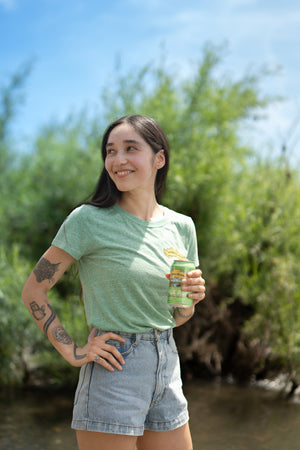 Thumbnail of Sierra Nevada Brewing Co. Women's Pale Ale T-Shirt worn by a woman standing on the bank of a river enjoying a Pale Ale