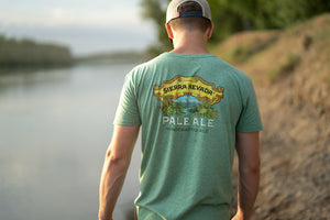 Thumbnail of A man walks along a peaceful river wearing the Sierra Nevada Brewing Co. Pale Ale t-shirt, as viewed from behind.