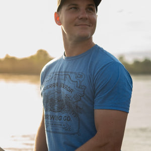 Thumbnail of A man wears the Sierra Nevada Brewing Co. Handcrafted T-Shirt while fishing along the riverbank.