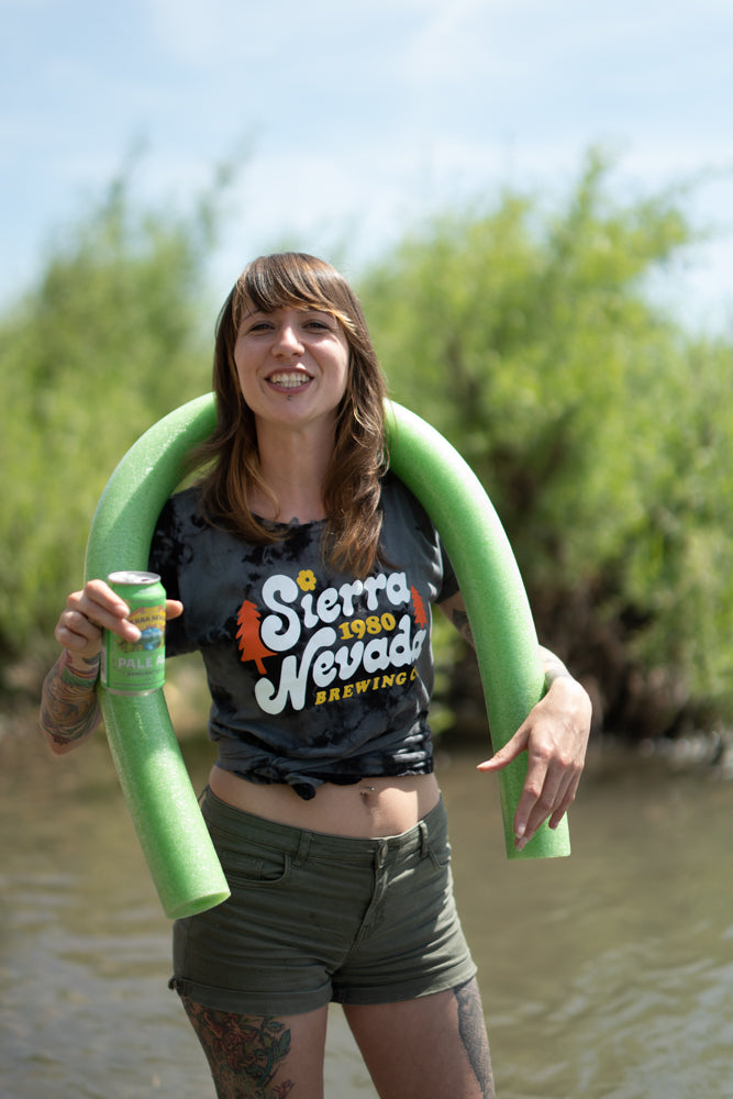 A woman wears the Sierra Nevada Brewing Co. Acid Washed Retro T-Shirt during a tubing adventure on a river.