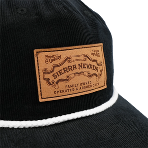 Thumbnail of Close-up of a black corduroy cap with a white rope trim and a tan leather patch reading 'SIERRA NEVADA' on a white background.