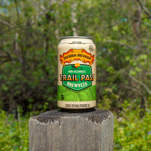 Thumbnail of Sierra Nevada Trail Pass Brewveza can perched on top of a wooden fence post in front of a wooded area