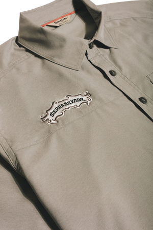 Thumbnail of A close-up of a light gray collared button-up shirt with a white embroidered 'Sierra Nevada' logo patch on the chest, set against a dark background.