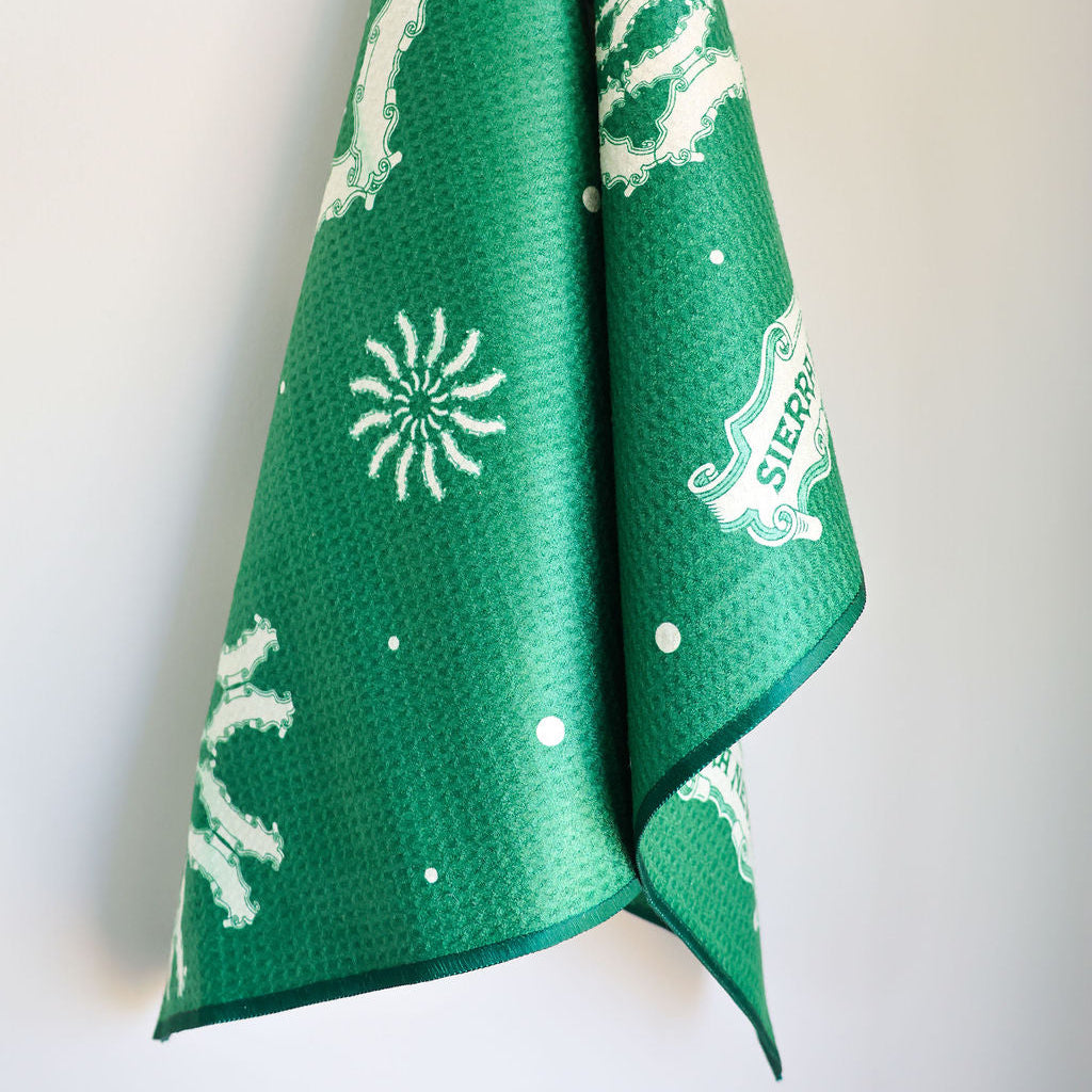 Green towel with white patterns hanging on a white background