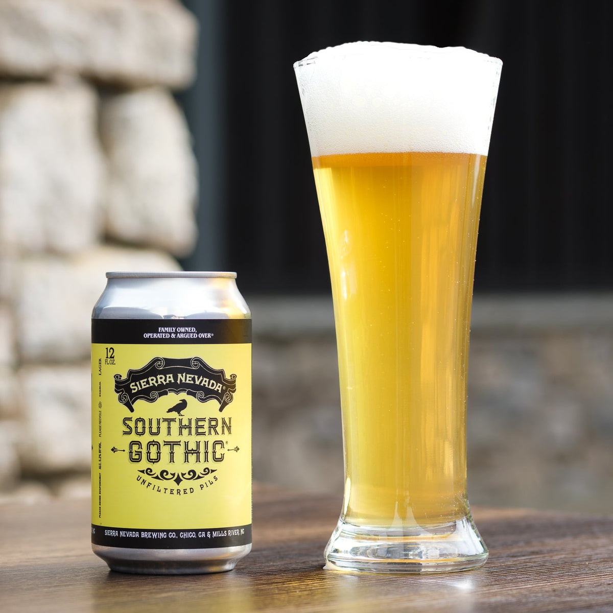 Sierra Nevada Southern Gothic beer can and glass on a wooden surface with blurred stone wall background