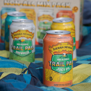 Thumbnail of Cans from the Sierra Nevada Trail Pass Variety Pack sitting on a picnic blanket in front of the packaging