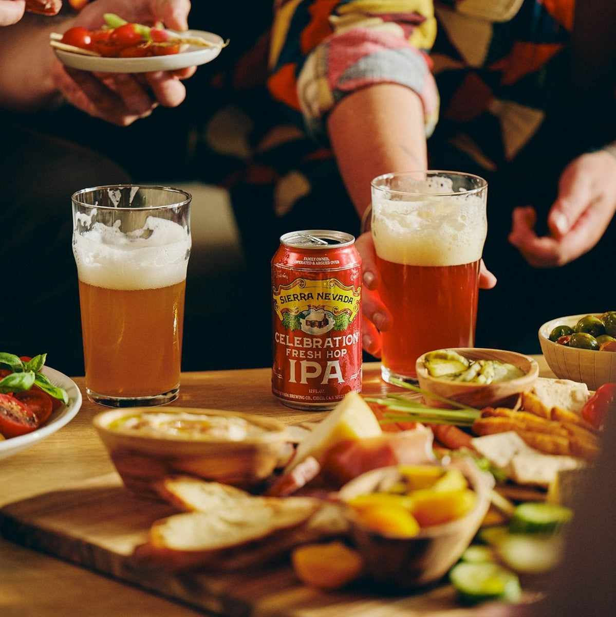 A can and glass of Sierra Nevada Celebration IPA on a coffee table covered with snack foods