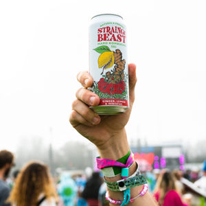 Thumbnail of Person in a crowd holding a can of Strainge Beasts Ginger, Lemon & Hibiscus hard kombucha